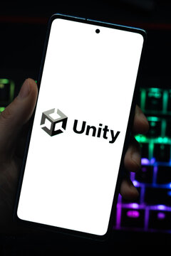 Punta Arenas, Chile &ndash; April 30, 2026: Close-up of the Unity game engine brand logo on a mobile phone screen held by a hand over a dark desk with glowing RGB keyboard lights