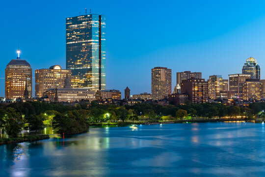 Boston city lights shine across the Charles River at twilight, showcasing the architectural beauty of the downtown and back bay buildings.