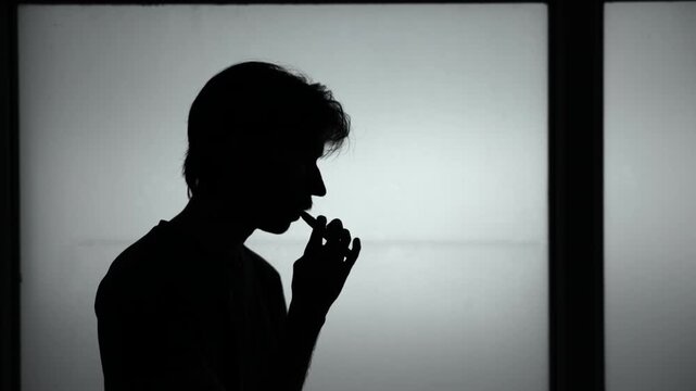 College Student Takes Silent Vape Pause. Silhouette Of Individual Releasing Vapor During Study Session . Media