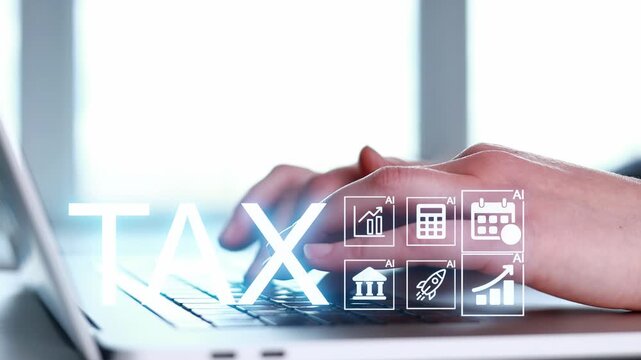 Hands typing on a laptop with tax icons displayed on the screen during a work session in an office setting.