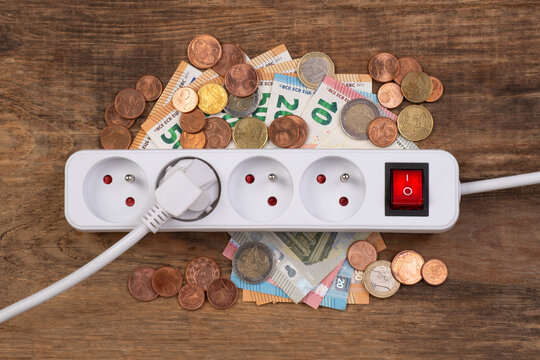 Cost of electricity concept, plastic power strip and money on a wooden background