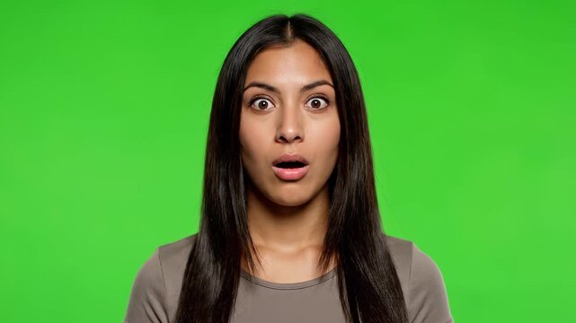 Astonishment: An expressive young woman is filled with wonder and surprise, her eyes wide and mouth agape against a vibrant green backdrop.