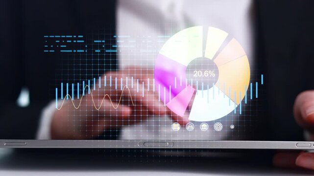 Person uses tablet to analyze data with colorful charts and graphs during a business meeting in an office setting.