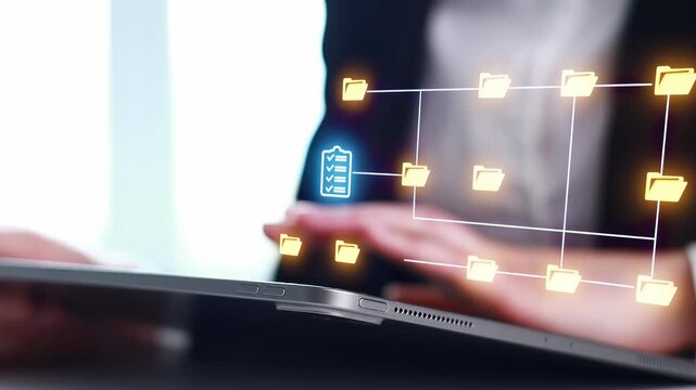 Using a laptop to manage digital files and organize tasks in an office setting in the afternoon.