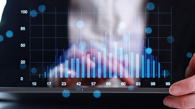Business person reviews data trends on a tablet screen with blue and white graphs during a meeting in an office setting.