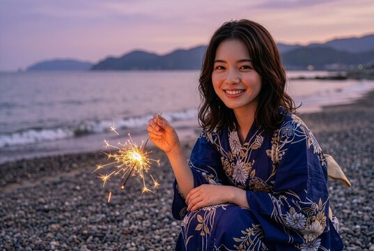 Woman in yukata holding a sparkler on the beach at night, Japanese summer festival scene