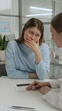 Vertical view of IVF doctor supporting disappointed gen Z girl getting emotional after hearing bad news in clinic