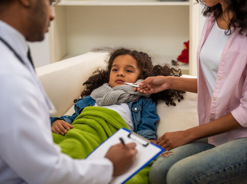 Doctor checking sick child temperature.