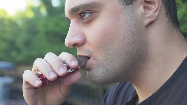 Overweight man eating a chocolate wafer snack