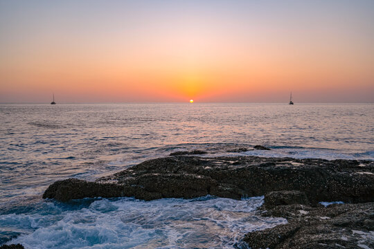 A vibrant sunset paints the sky orange and pink over the tranquil ocean