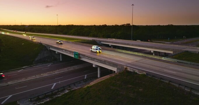 Aerial view of rural freeway junction with fast moving cars and trucks at sunset. Key part of American transportation infrastructure