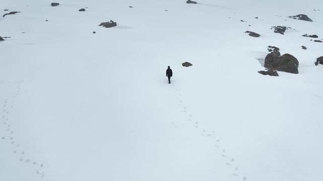 Drone shot revealing a Traveller walking at snow-covered Phase 2 Gondola station in Gulmarg.