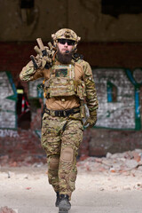 Naklejka premium Armed Tactical Soldier in Camouflage Gear Walking Through Urban Ruins With Rifle and Helmet