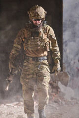 Fototapeta premium Soldier in Tactical Gear Walking Through Dusty Urban Ruins With Rifle and Camouflage Uniform