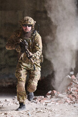 Naklejka premium Bearded Special Forces Soldier Running Through Dusty Urban Ruins With Rifle And Tactical Gear