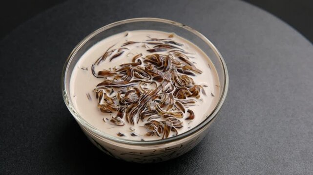Cincau or Grass Jelly noodles with milk.Chinese vegetable jelly black in color served with milk in glass bowl.
