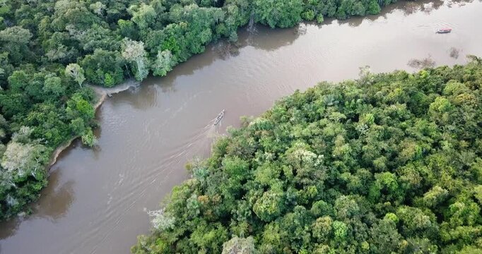 Aerial tracking shot of small boat on Amazon river near Iquitos Peru smooth drone flying over rainforest 4K