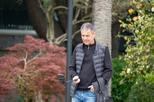 senior man in park making video content with a phone