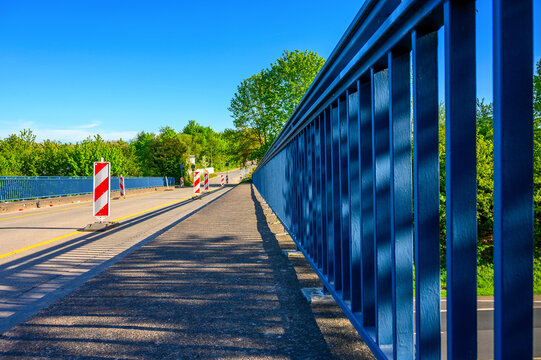 Blue bridge railing with traffic signs and clear blue sky on a sunny day