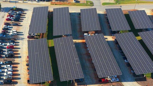 Green energy production from solar panels installed above city parking lot. Dual-purpose photovoltaic roof offering shade and renewable electricity.