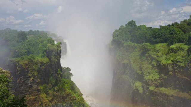 Majestic Victoria Falls in Africa displaying immense power with Zambezi river flowing into chasm creating large mist between Zimbabwe and Zambia borders