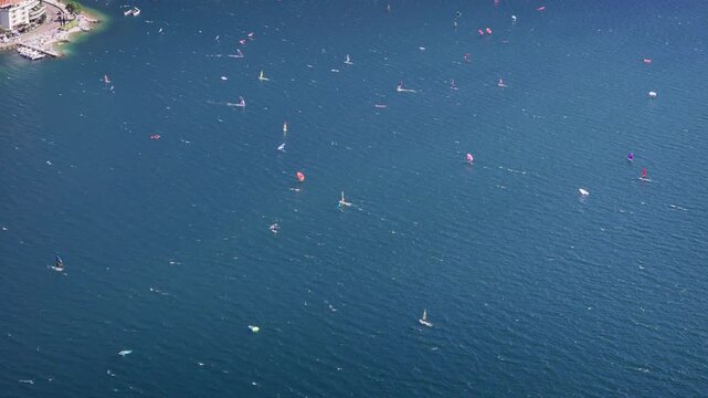 Windsurfing activity on Lake Garda, aerial wide shot. Sails on water surface near Torbole, popular sports destination in Italy