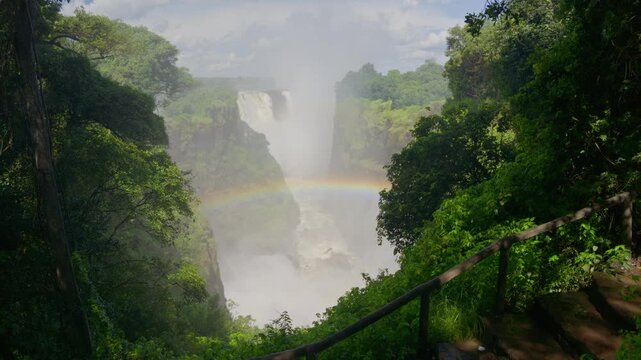 Victoria Falls generating abundant mist and vibrant rainbow over Zambezi River between Zambia and Zimbabwe, highlighting power of nature and African landscape