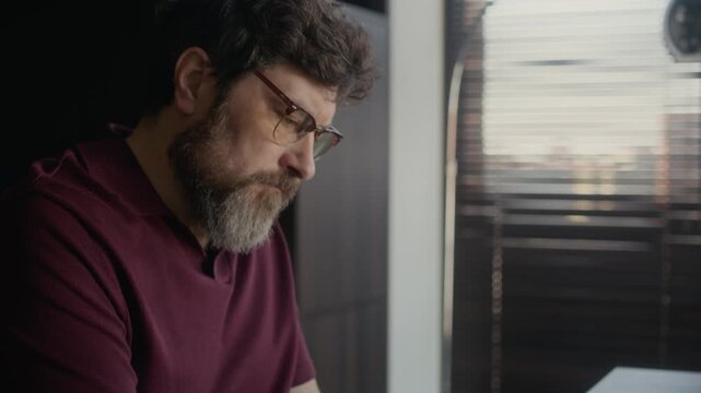 Close up of bearded middle aged Caucasian writer working on script in modern home office, marking up paper draft