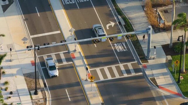 Pedestrians hurry across a busy zebra crossing in downtown Sarasota as traffic slows at the intersection, capturing the fast-paced rhythm of modern city life in Florida.