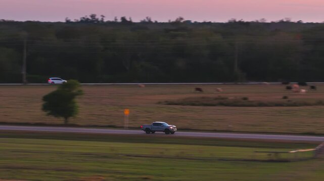 Pickup truck driving along a straight road through open land, evening light illuminating highway, symbolizing direction, journey and destination.