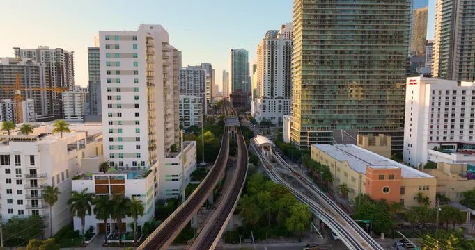 Public train system in urban landscape of downtown Miami Brickell in Florida, USA. Tracks threading between skyscrapers at sunset.