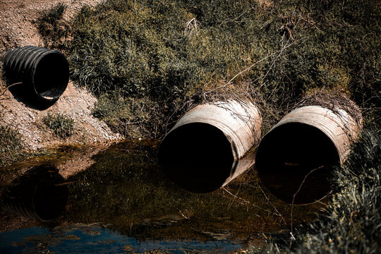 Flood flow fills drainage ditch fast. Flood water passes through culvert pipe. Sustainable systems reduce flood near creek. Environmental drainage limits flood and erosion.