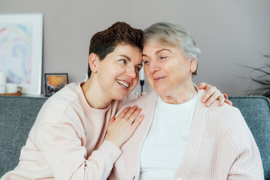 Emotional Adult daughter hugging happy senior 70s mother in cozy interior. Mother day. Happy family enjoying weekend together. Parenting love, care, generations unity. Spending time in retiring house