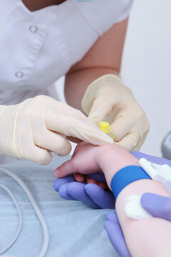 Nurse inserts medical catheter into child's arm. Inserting catheter into vein. Child is under anesthesia. Concept of healthcare and medicine.