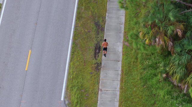 Runner moving fast on residential street sidewalk. Aerial view capturing athletic activity, movement and healthy outdoor lifestyle