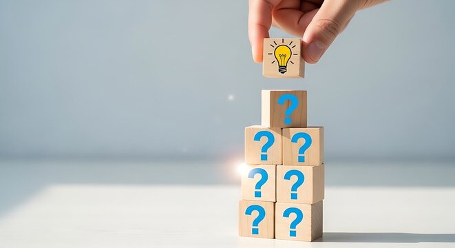 A hand holding a wooden block with a lightbulb on top of a stack of blocks with question marks, symbolizing a bright idea or solution to a problem or puzzle
