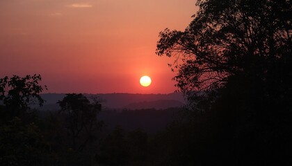 Obraz premium Beautiful sunset landscape with mountains and forest under a colorful sky filled with clouds and trees.