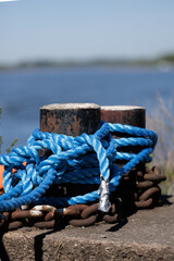 Fototapeta premium Relaxing Seaside Setting Emphasizing Rusted Post Entwined With Twisted Blue Cord And Radiant Sunlight
