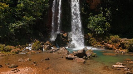 Obraz premium Waterfalls cascading down rocky cliffs, forming a tranquil stream in lush nature