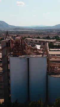 Abandoned cement factory with large silos and rusty industrial structures