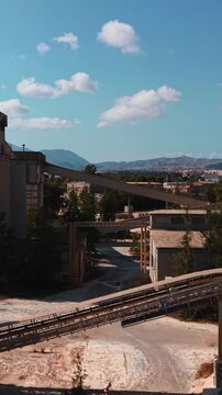 Derelict industrial complex with rusty silos and conveyor belts on a sunny day