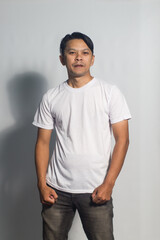 Obraz premium An Asian man from Indonesia standing wearing a white t-shirt. Isolated on a white background.