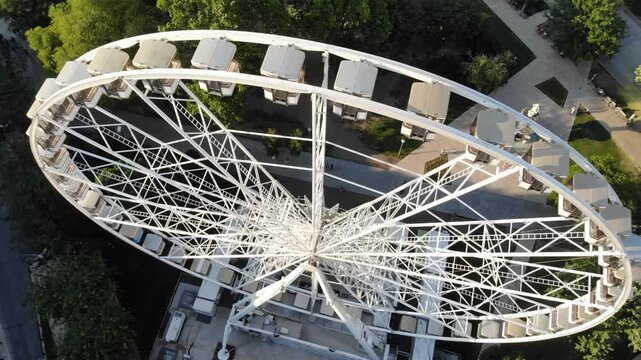Close up view of a Ferris wheel structure with cabins in an urban environment. Detailed perspective of amusement ride construction, symbolizing entertainment, tourism and city lifestyle.