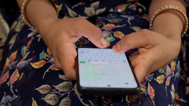 Close-up of an Indian woman in traditional attire typing a message on her smartphone indoors