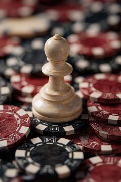 Symbolic pawn chess piece surrounded by oversized poker chips out of place overwhelmed concept