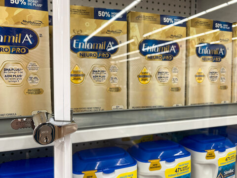 Closeup on Enfamil baby formula containers secured behind locked glass cabinet at Walmart grocery store. Concept of retail theft prevention. Aurora, Ontario, Canada, April 2026