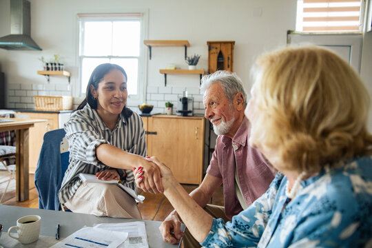 Financial advisor shaking hands with senior couple at home