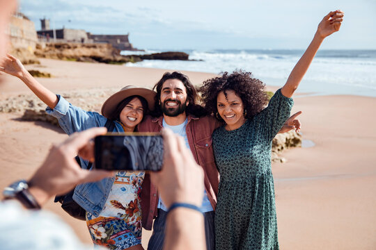 Three friends posing for smartphone photo on sunny beach