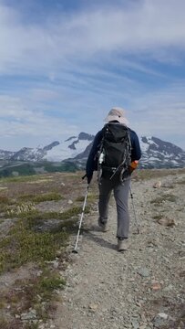 Adventurous Hiker Treks Rocky Mountain Trail Towards Majestic Snowy Peaks in British Columbia
