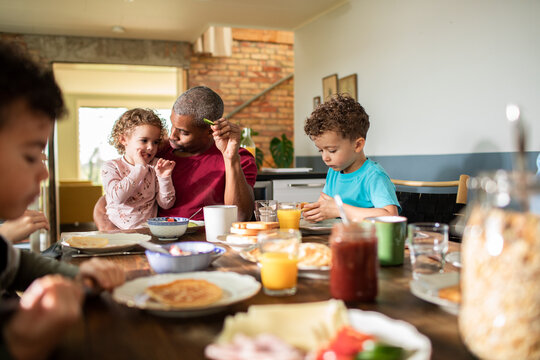 Father with young children eating breakfast at home